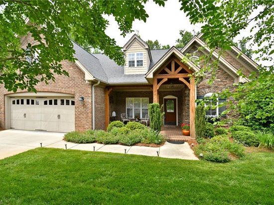 Brick and stone craftsman home with timber-framed entry and lush landscaping sold by Rob Herald Realty in the NC Triad